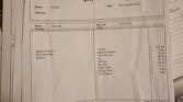 A stack of printed invoices lies on a surface, with the top one from "John Tite Car Repairs Ltd." dated November 9, 2022. A handwritten note on the top invoice reads, "Chq 11.11.22 sent whuuuuy!" Visible charges include MOT check, oil for a MINI, filter, anti-freeze, and brake fluid.