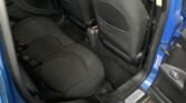 Interior shot of the back seat of a blue MINI COUNTRYMAN. The image displays black fabric upholstery on the rear seats and the back of the front seats. The clean floor with visible seat belts and car door handles, along with the legroom area and door sills, showcase a well-maintained COOPER 1.6.