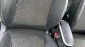 A close-up view of a MINI's front seat with a combination of leather and fabric upholstery. The seat features a vertically striped fabric center and smooth leather sides. Visible beside the seat are a center armrest and part of the console area with cup holders and controls.
