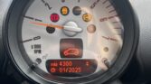 Close-up view of a MINI's dashboard with a tachometer displaying a needle at 0 RPM. Warning lights are illuminated, including check engine, oil pressure, and tire pressure symbols. An odometer screen below shows a mileage of 4300 and a date of January 2025. Background is slightly blurred.
