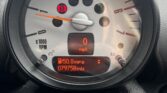 A close-up of a MINI's speedometer and odometer display. The speedometer reads 0 mph, and the tachometer shows 0 RPM. Indicator lights, including one with an exclamation mark in a circle, are illuminated. The digital display shows 50.8 MPG, and the odometer reads 079758 miles.
