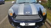 This Mini Countryman Cooper D 1.6 is a 5-door hatchback with Cosmic Blue exterior & silver stripes with a White Roof and Silver roof rails.Interior is black with grey cloth seats and a centre rail which holds a mini glasses case