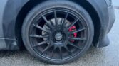 Close-up of a car’s front wheel featuring a black alloy rim with multiple thin spokes and a central hubcap marked with “Mexico” branding. The tire brand “DAVANTI” is visible. Behind the rim, a red brake caliper can be noticed. The grey MINI is parked on an asphalt surface.