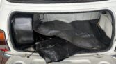 The image shows an open trunk of a white MINI car. Inside, there is a black rubber mat and some black equipment. A sticker on the rear window reads "I ♥ MY MINI" with smaller text below, and the "Friary Motor" emblem is visible. The trunk lid is up, revealing the contents.