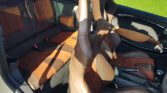A MINI's interior featuring leather and suede upholstery. The front seats are tan-colored racing-style bucket seats with cutouts near the headrests. The dashboard and door panels are finished in black and tan leather. Sunlight streams in, casting shadows on the seats and carpet.