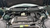 A mini car with its hood open showing the engine bay; visible are the engine, battery, reservoir, and various hoses and components. The car’s license plate reads "WP52 YZB." The vehicle is parked outdoors on a gravel surface—perfect for any mini trader.