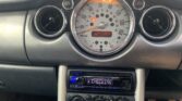 The photo shows the dashboard of a mini car. The large central speedometer reads 0 mph, with a digital odometer below displaying 113556 miles. Below, a car stereo with a blue display reads "CHECKING." Air vents and control dials are also visible.