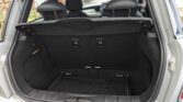 Open trunk of a small silver mini car with black interior. The back seats are upright, and there’s a cargo net on the floor of the trunk. The trunk appears clean and empty, with a view of the front seats and dashboard through the rear—a perfect mini trader setup.