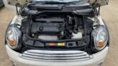 The image shows the open hood of a white mini car, revealing its clean and well-organized engine bay. The headlights, chrome grille, and UK license plate "YK61 XNL" are visible—an appealing sight for any Mini trader or enthusiast.