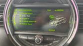 A mini dashboard display shows service requirements—brake fluid, engine oil, vehicle inspection, and vehicle check—all marked "OK." The screen features a digital mini car graphic, date 07/2025, and is framed by a circular trim with buttons below.